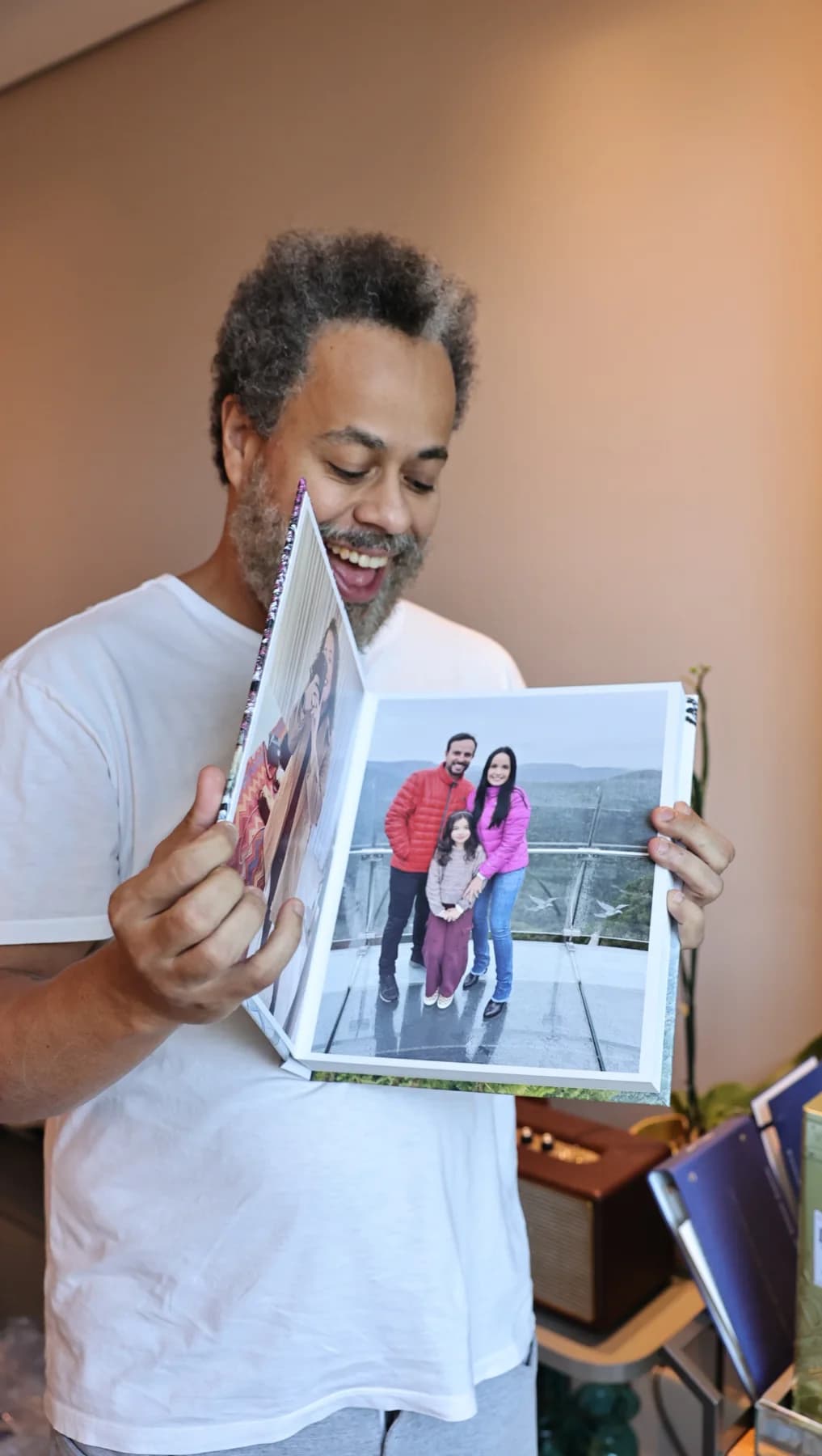 Jairo sorrindo ao rever as memórias da família no álbum aberto